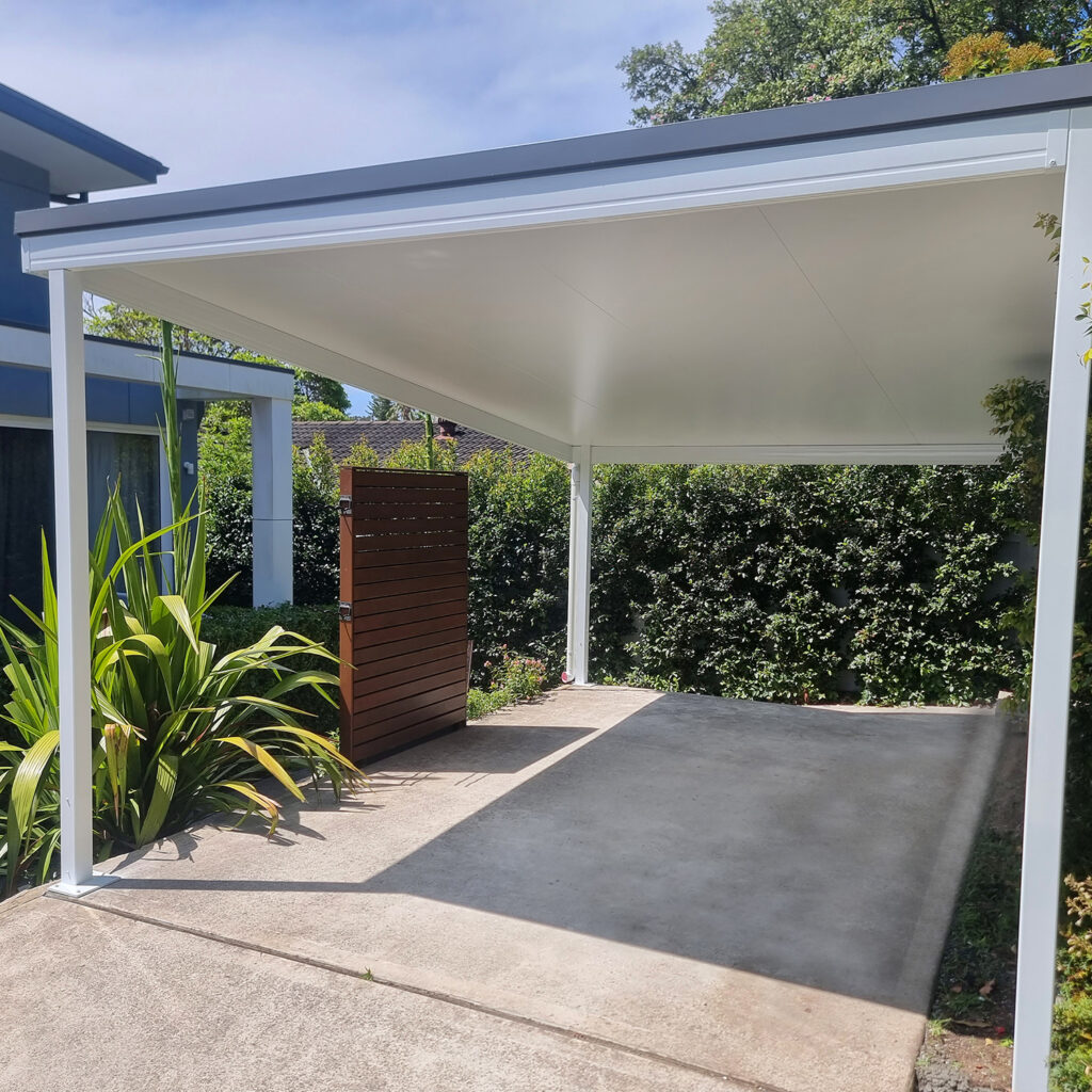Modern DIY attached flyover flat roof patio/pergola with landscaped garden in background.