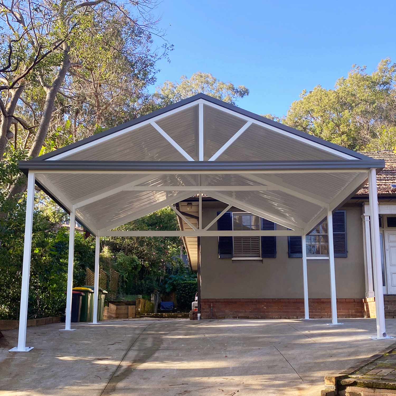DIY freestanding gable roof carport with white roof and pillars.
