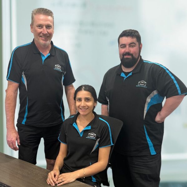 Three team members in branded uniforms posing together.
